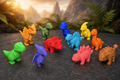 Doze mini dinossauros chibi coloridos impressos em 3D sobre rocha